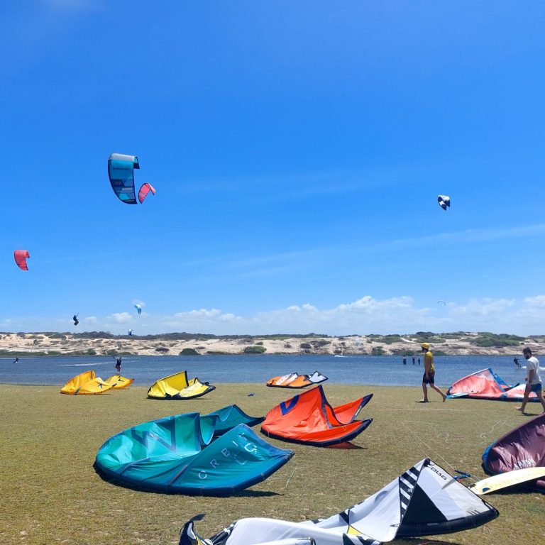 Gruppe von Menschen sitzt auf einer Sanddüne bei Sonnenuntergang.