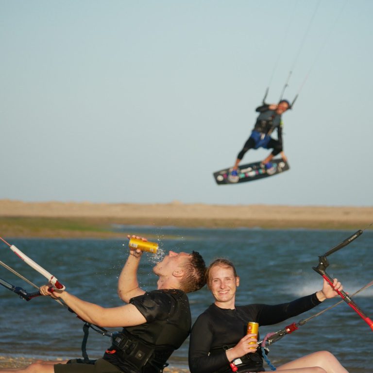 Person kitet über das Wasser, während eine Hand eine Kokosnuss hält.